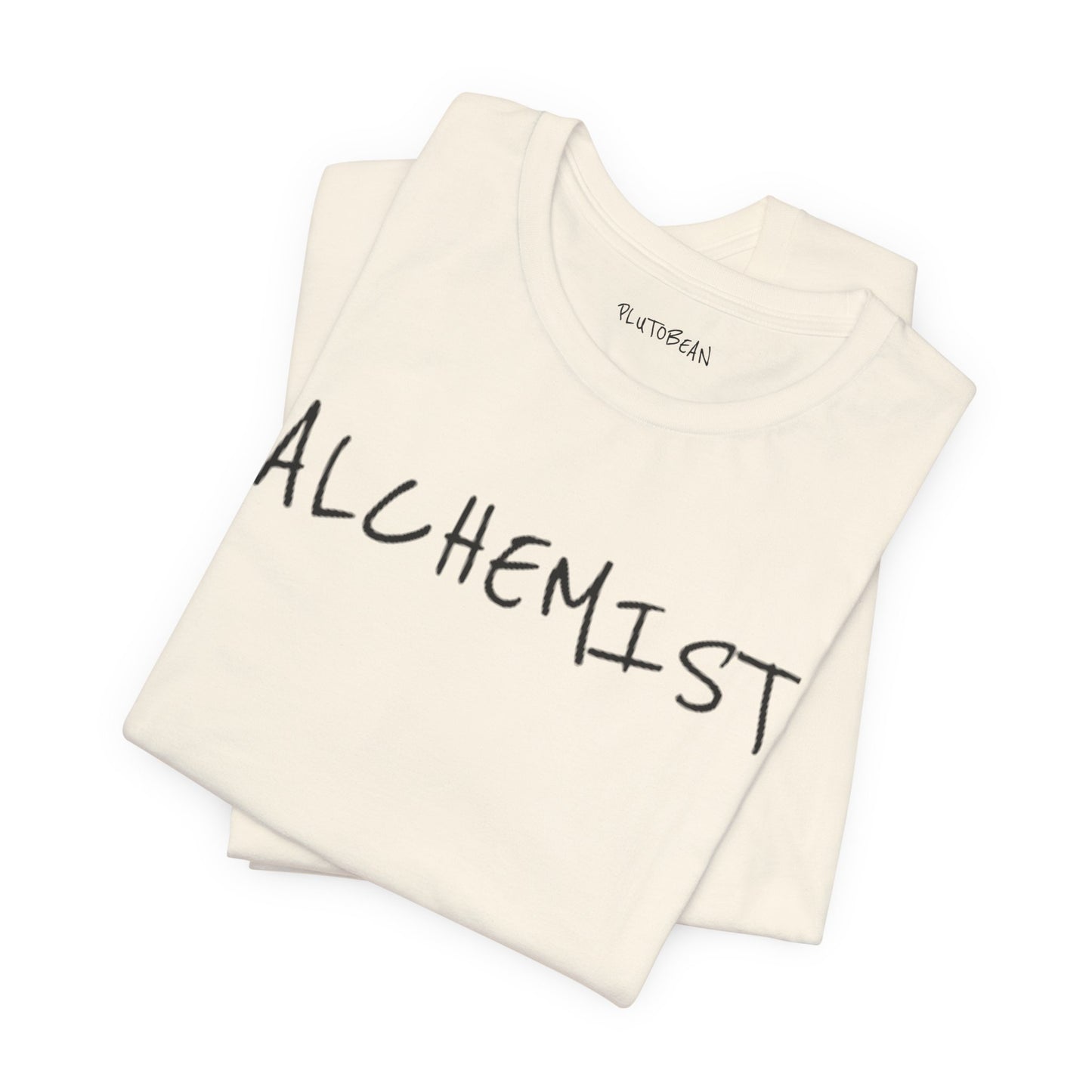 Folded natural tee featuring handwritten black “ALCHEMIST” wordmark