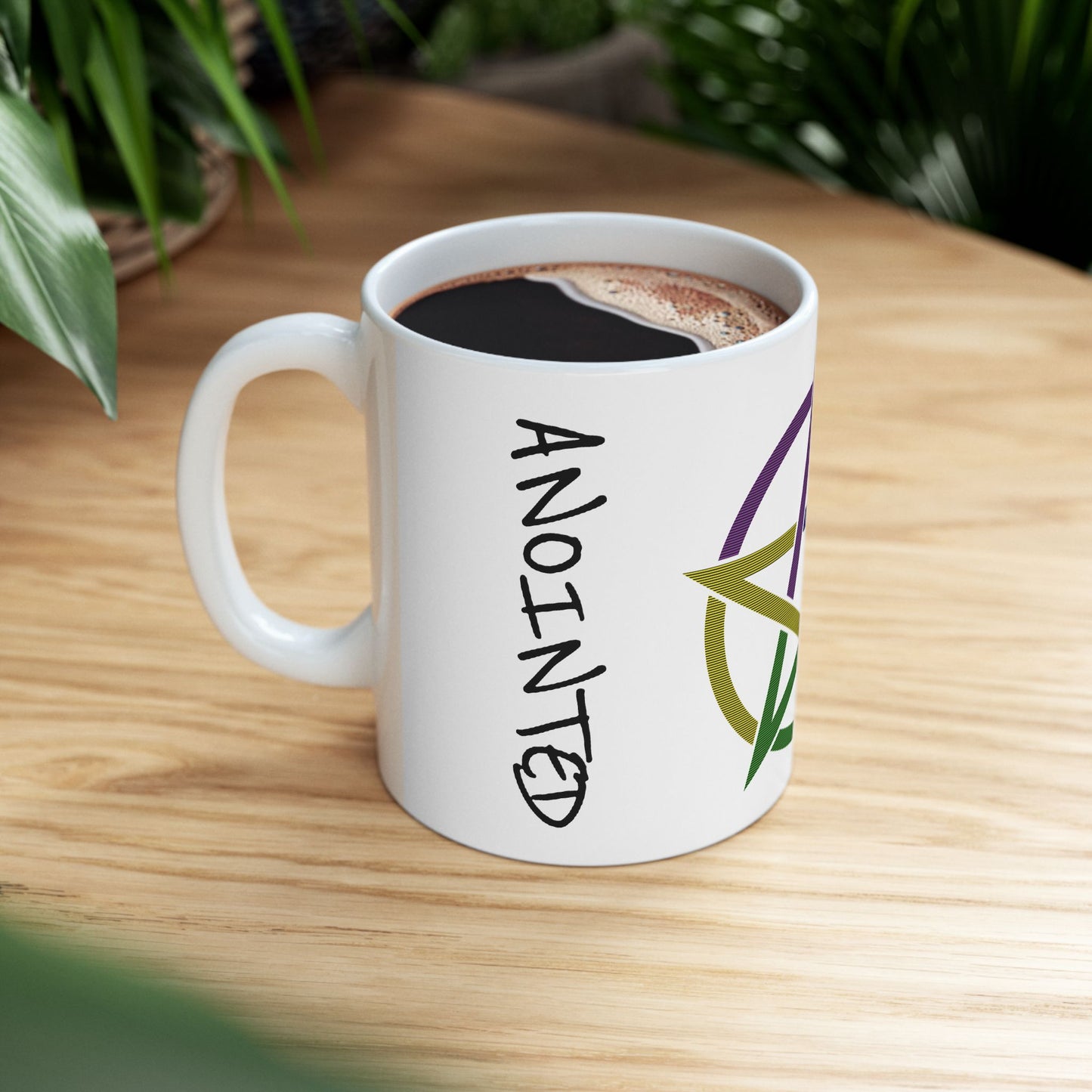White mug with 'ANOINTED' text and logo on a wooden table